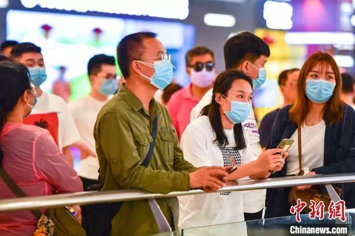 图为佩戴口罩的民众在海口美兰国际机场到达厅迎接亲友。　骆云飞 摄